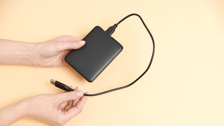 Close-up of hands holding external hard drive