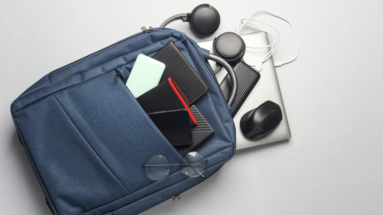 Headphones, a smartphone, a laptop, a power bank, and other items in small carry-on.
