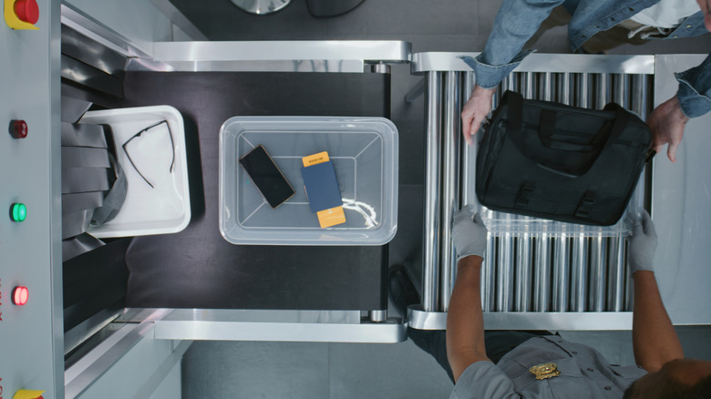 Top-down view of TSA security checkpoint conveyor with filled bins.