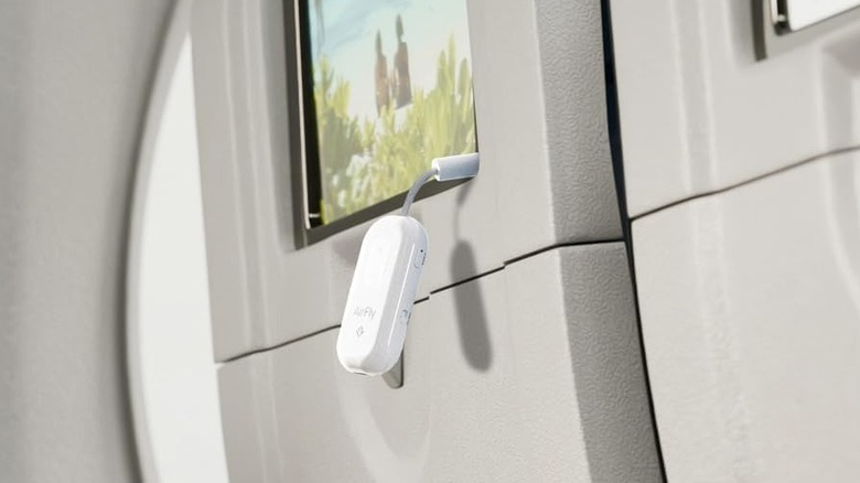 Several travelers sitting on a plane using in-flight entertainment