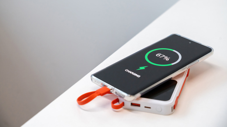 A power bank charging a phone on a white table