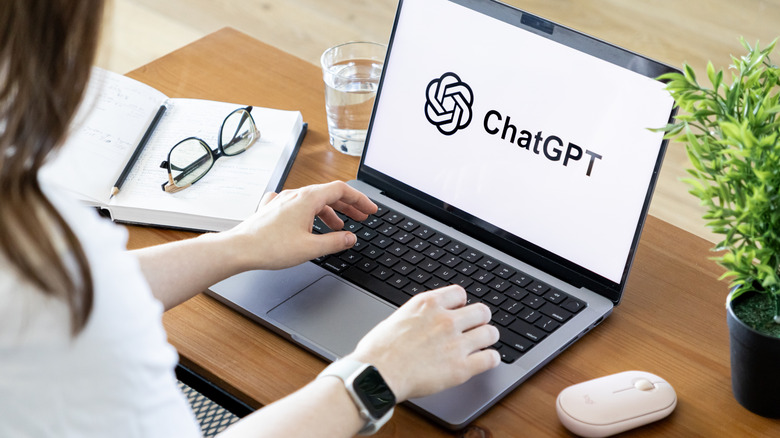A photograph of a woman working at a laptop that has the ChatGPT logo displayed on the screen.