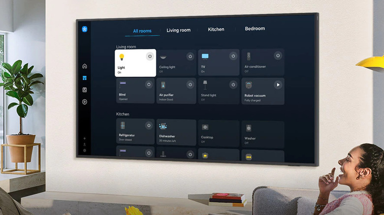 Person laughing with smart TV in background showing Samsung SmartThings app main menu