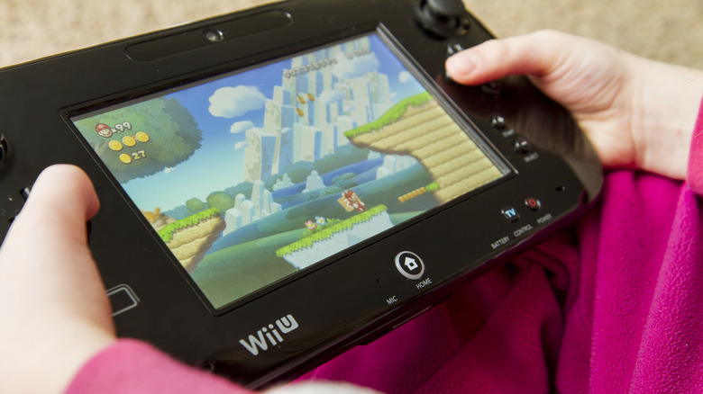 A person holding a black Wii U gamepad playing New Super Mario Bros. U
