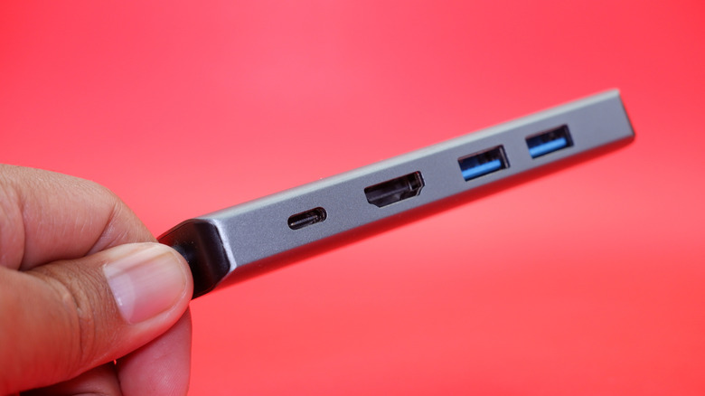 Hand holding USB hub with multiple ports on red background