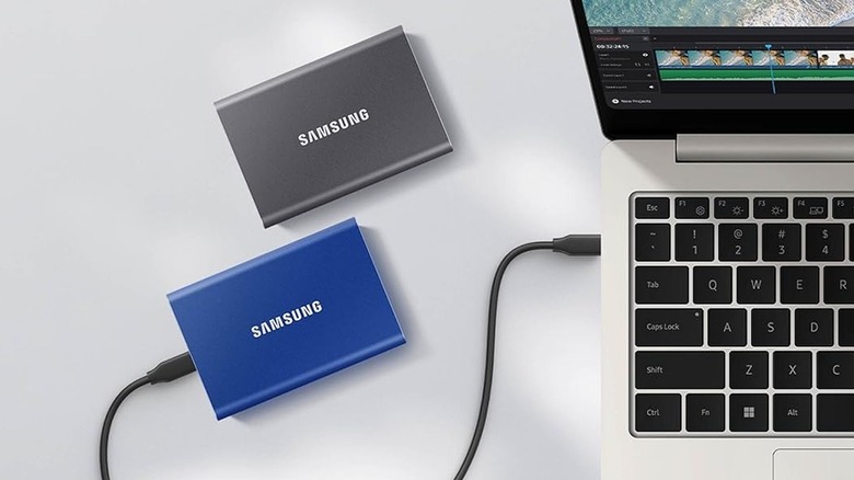 Two Samsung T7 SSDs on a tablet, of which one is connected to a MacBook
