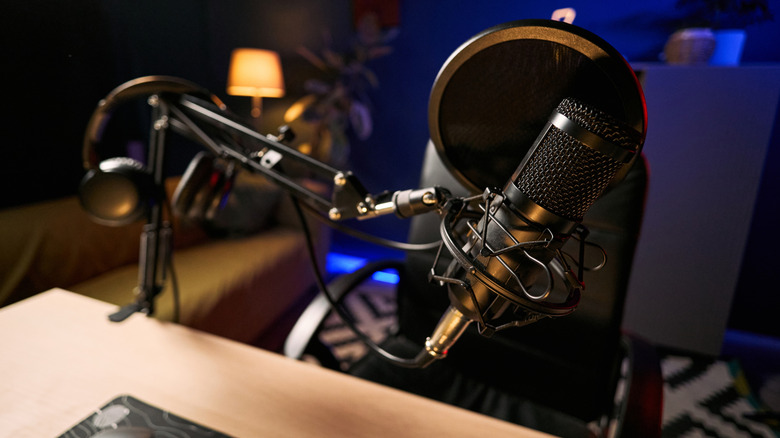 A podcast microphone with a pop filter and headphones in a recording setup.