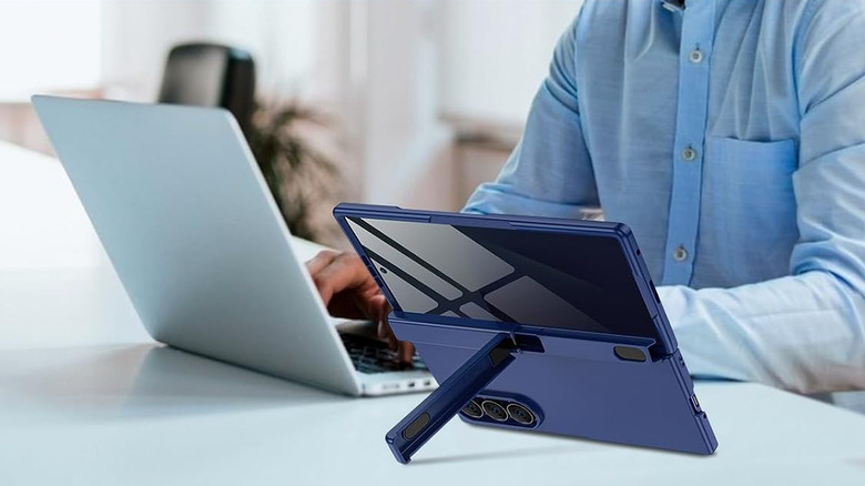 Blue hinge case with a built-in kickstand attached to a foldable phone on a desk beside a laptop.