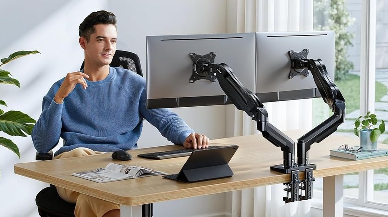 Person at computer using dual monitors on arms