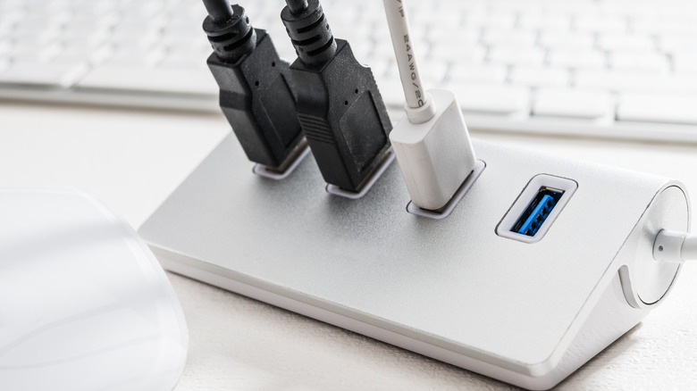 A white USB hub with three USB cables plugged in