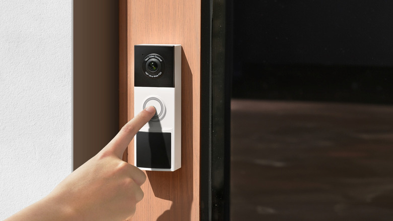 Close-up of a person ringing the TP-Link Tapo D205 mounted on a door frame
