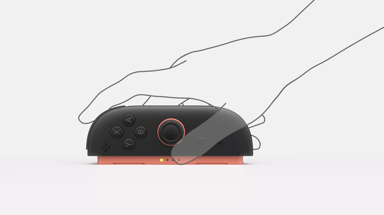 An outline of a hand demonstrating how to use a red Joy Con 2 as a mouse
