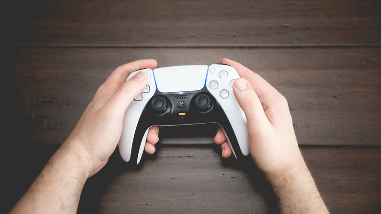 A person holding a DualSense Controller that's lit up at the edges of the center of the touchpad