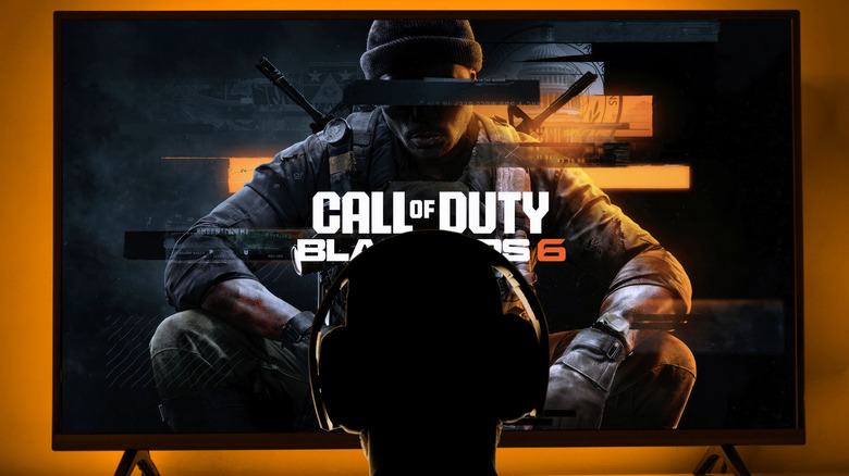 A person sitting in front of a tv with headphones showing Call of Duty Black Ops 6 on the screen