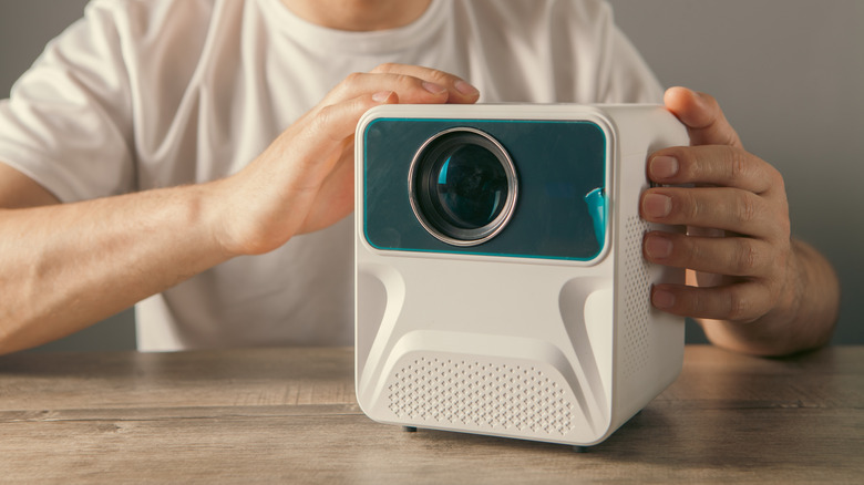 A person examining a small projector.