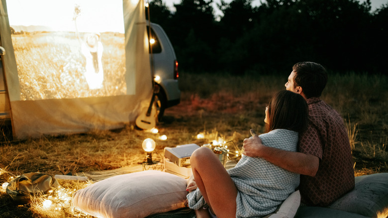 A couple watching a movie in an outdoor setting.