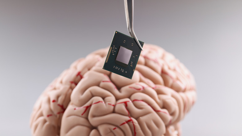Tweezers dropping a computer chip onto a brain
