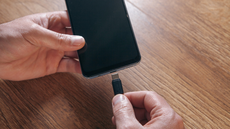 Hand connecting USB-C cable to phone