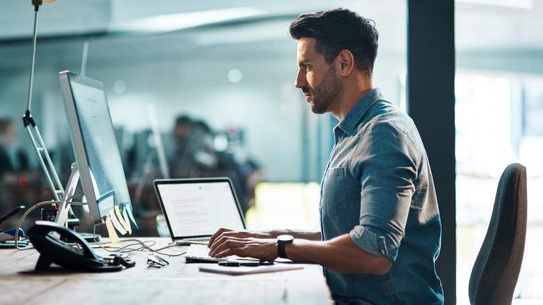 Side view of a man sitting at his desk.