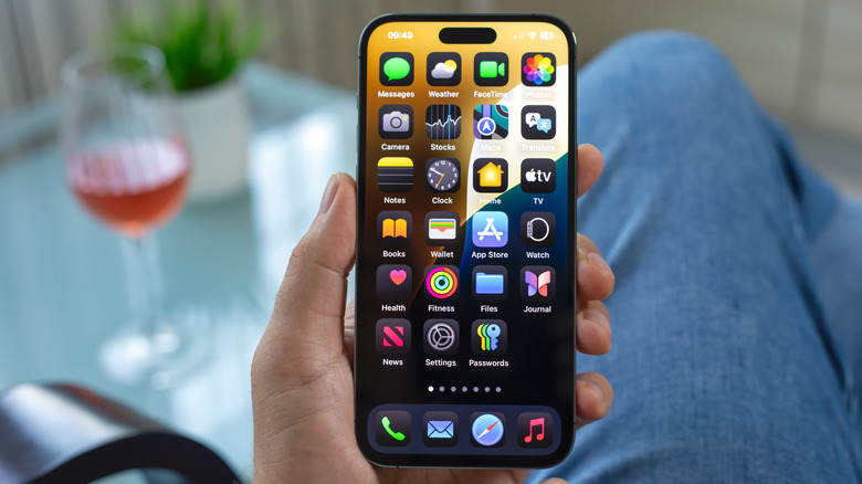 A person holding an iPhone in their left hand as they sit at a table