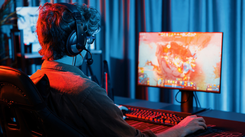 A young man playing a video game on a small, cheaper monitor