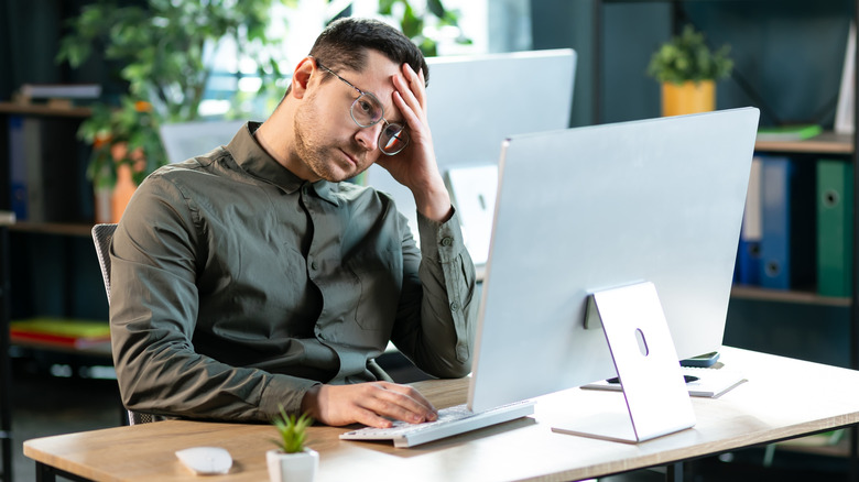 An office worker is frustrated at his PC monitor