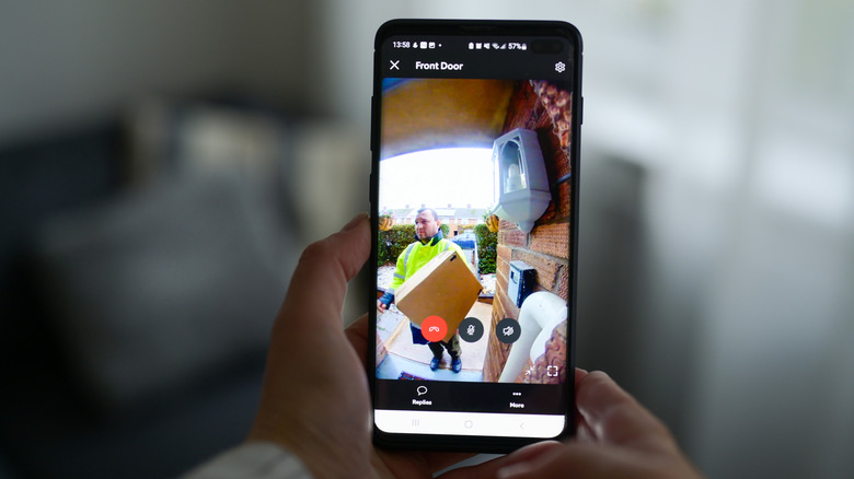 A person using a video doorbell app to watch a courier deliver a package.