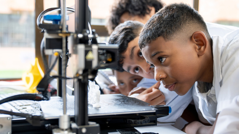 Several children watching a 3D printer work.