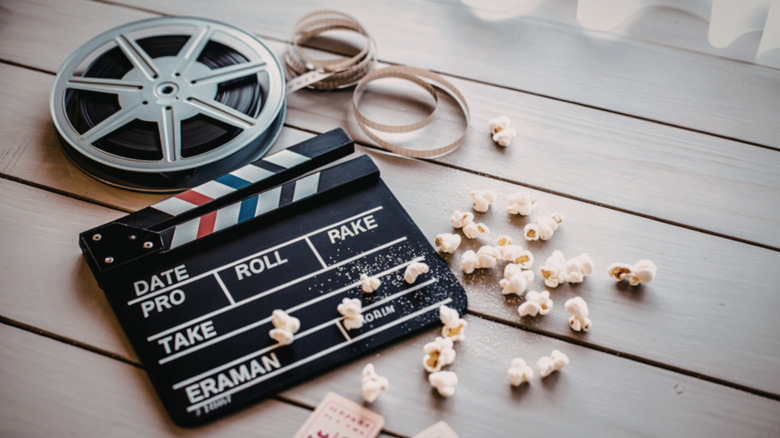 A clapboard, film reel, and movie tickets on a table