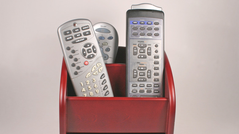 Several remote controls placed in a remote control caddy