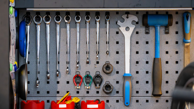 Various hand tools mounted on a gray metal pegboard.