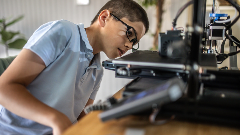 Close up of young boy using a 3D printer.