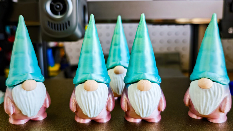 3D printed gnomes lined up in front of the printer.