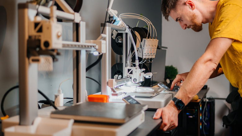 Designer interacting with a 3D printer's control screen.