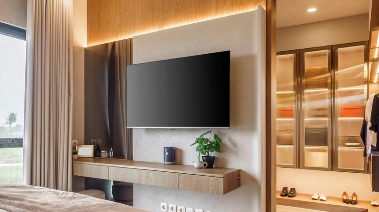 A flat-screen television mounted in a bedroom, the closet is open behind the TV