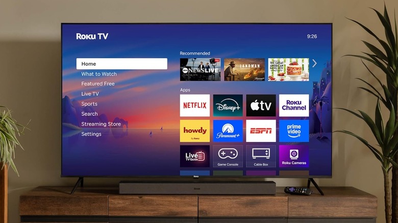 A Roku Smart TV Select Series 4K sitting atop a wooden stand in between two different plants