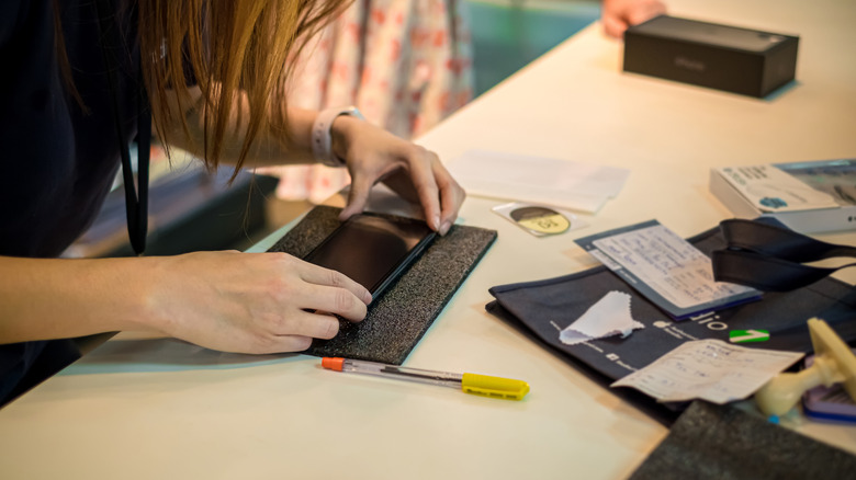 Woman hand putting the screen protector glass on Apple iPhone 11 Pro Max.