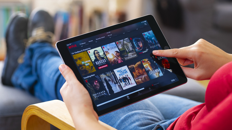 A person using an iPad to browse TV shows in the Netflix app.