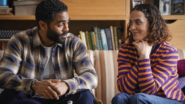 Tiffy (Jessica Brown Findlay) and Leon (Anthony Welsh) talking to each other on a sofa in The Flatshare
