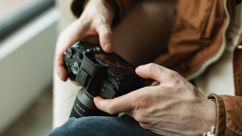 Person holding a compact mirrorless camera in both hands.