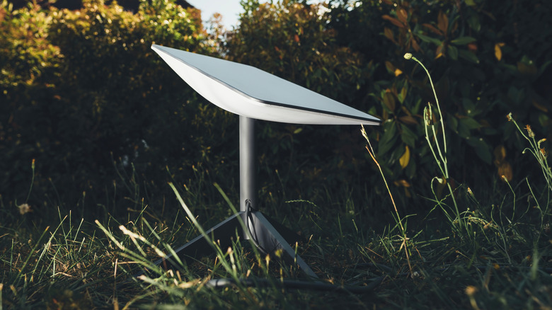 Starlink satellite dish set up on grass outdoors.
