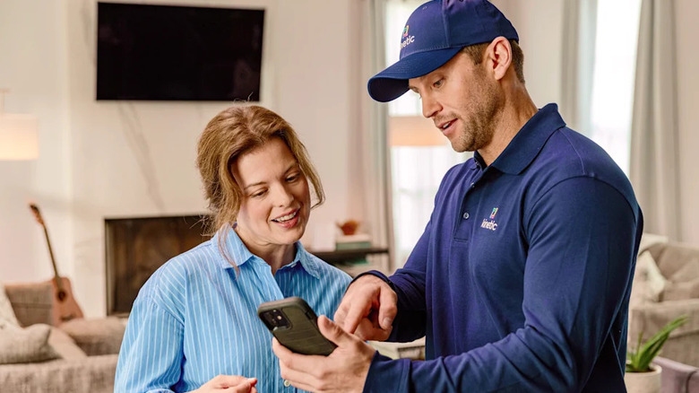 Kinetic technician showing a smartphone to a customer inside a home.