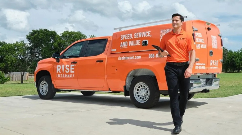 Rise Internet technician walking beside an orange service truck.