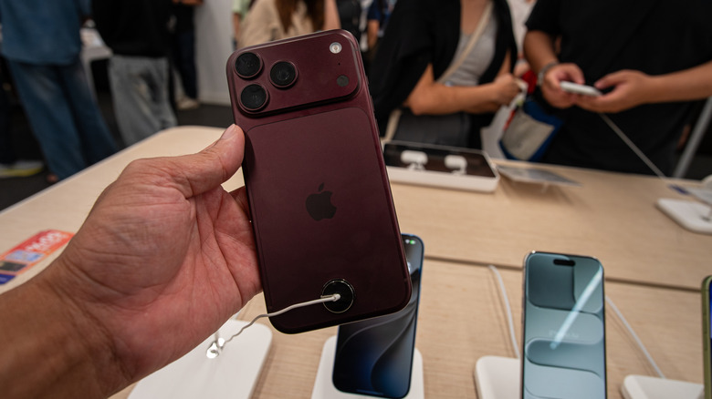 Person holding burgundy iPhone 18 Pro in Apple store.