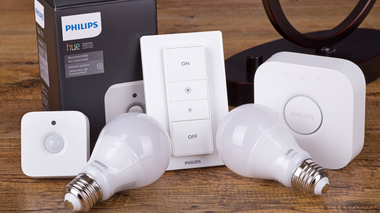 Philips Hue smart bulbs resting against accessories including smart light switch and Hue Bridge.