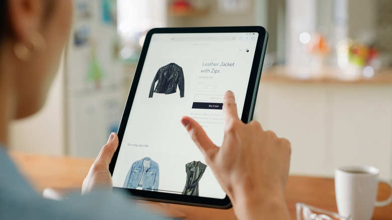 Person shopping online on a tablet while viewing a clothing product page.