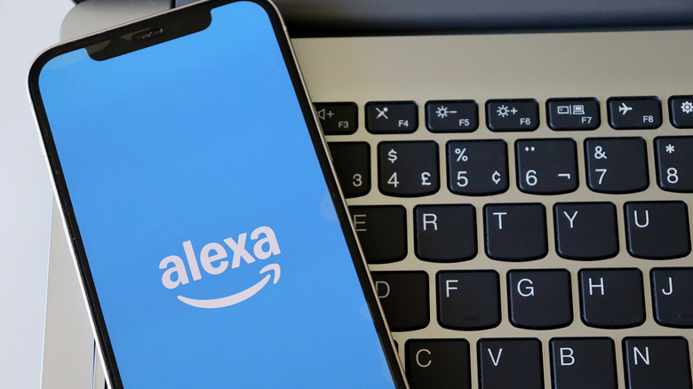 alexa logo on smartphone atop laptop