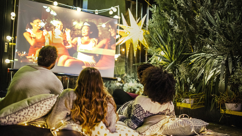 Three people watching a movie on a projector screen.