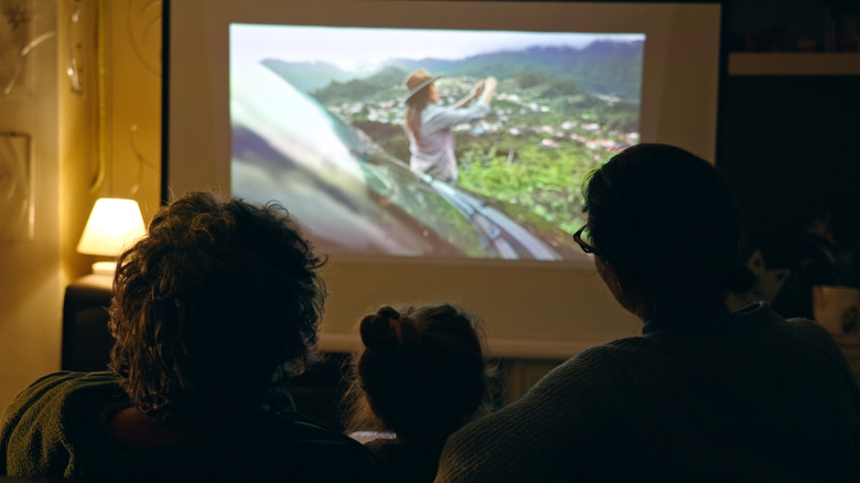 A family watching a movie on a home projector screen.