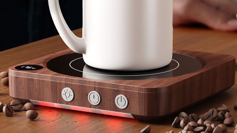 A white mug warming on a House Gem Mug Warmer, glowing orange-red on the bottom panel